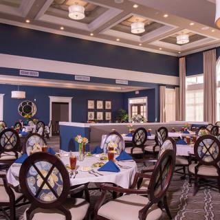 An elegant dining room set up with round tables and formal place settings.