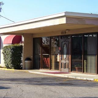 A view of a commercial building with a covered entrance and landscaping.