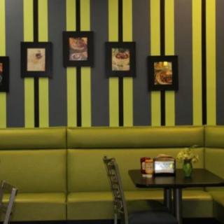 A modern restaurant interior with green and black striped walls, featuring framed artworks and cozy seating arrangements.