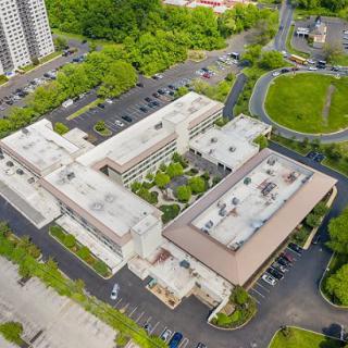 An aerial view of a large building complex surrounded by parking lots and greenery.