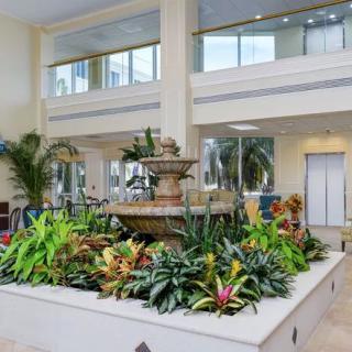 A spacious lobby featuring an elegant indoor fountain surrounded by lush greenery.