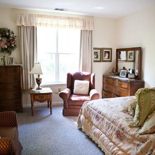 A cozy, traditionally furnished bedroom with an armchair and window.
