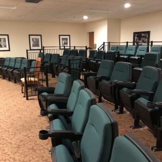 An empty auditorium with green seats arranged in rows.
