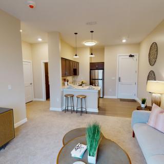 A cozy, modern apartment featuring an open-plan living and kitchen area with stylish furniture and warm lighting.