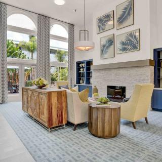 A beautifully designed living room featuring modern furniture, a cozy fireplace, high ceilings, and large windows.