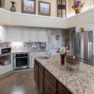 A modern kitchen with white cabinets, granite countertops, and stainless steel appliances.