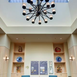 A modern interior space featuring a contemporary chandelier, with decorative shelving and artwork on the walls.