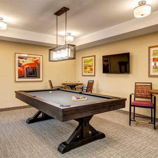 A modern game room featuring a shuffleboard table, contemporary artwork, and comfortable seating.