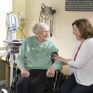 A caregiver interacts with an elderly person in a healthcare setting.