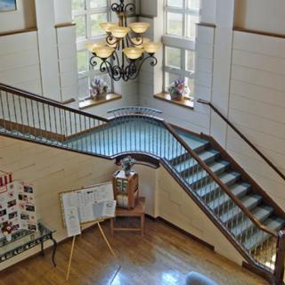 A grand staircase with a chandelier and large windows in a spacious interior.
