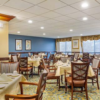 A well-lit dining area with neatly arranged tables and chairs, featuring elegant decor.