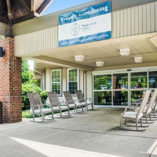 A building entrance with several rocking chairs arranged under a covered area.
