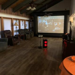 A cozy home theater setup with a large projector screen, comfortable seating, and warm wooden flooring.