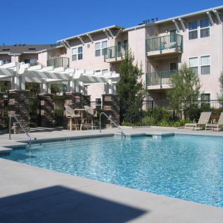 An outdoor swimming pool at an apartment complex, surrounded by balconies and seating areas.