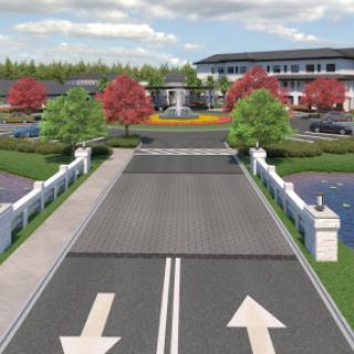A beautifully designed entrance showcasing a landscaped area with vibrant trees, water features, and a modern building in the background.