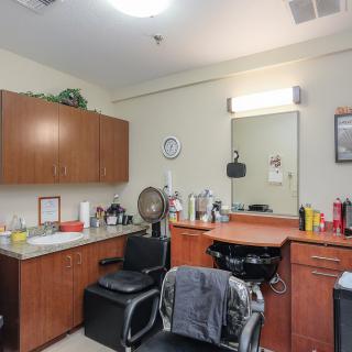 A well-equipped barbershop or salon interior featuring a hair cutting station with a mirror, chair, and various hair products.