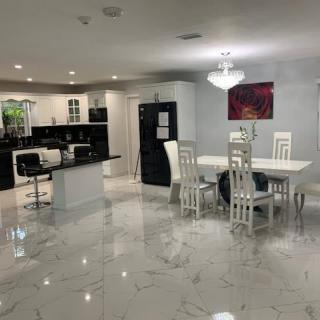 A modern open-concept kitchen and dining area with white decor and marble flooring.