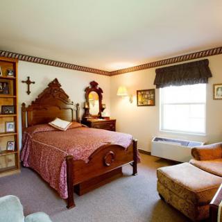 A cozy vintage-style bedroom featuring a wooden bed, bookshelf, and warm natural lighting.