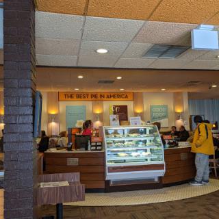 A lively cafe interior with customers enjoying their time and a display of tempting desserts.