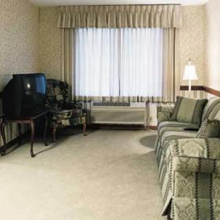 A cozy living room with a sofa, television, carpet, and curtains.