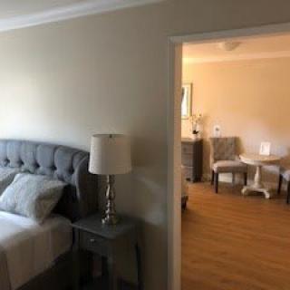 A cozy bedroom with a view into a living area, featuring modern furniture and decor.