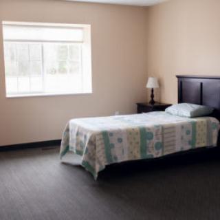 A minimalist bedroom with a single bed, nightstand, and lamp.