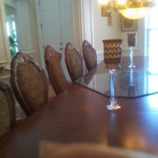 A dining room featuring a long wooden table with elegant chairs and a chandelier overhead.