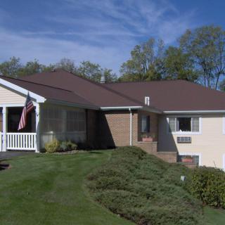 A suburban house with a well-maintained lawn and clear blue sky.