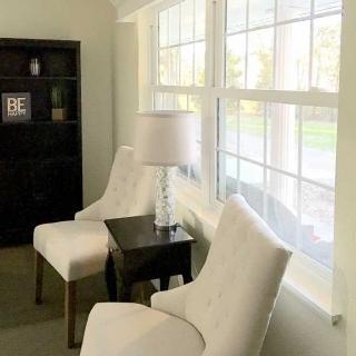 A cozy living room corner with two chairs and a lamp by the window.