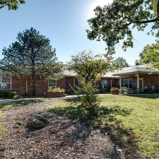 A suburban house with a well-maintained yard, surrounded by trees on a sunny day.