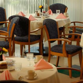 A cozy dining area with elegantly set tables, complete with pink napkins and glasses.