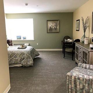 A cozy bedroom with a neatly made bed, desk, and decorative elements creating a comfortable atmosphere.