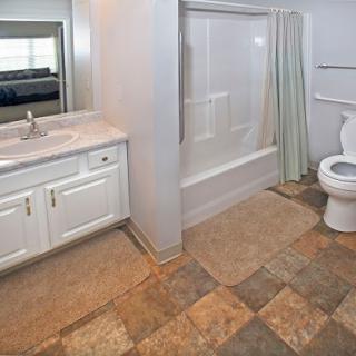 A modern bathroom featuring a bathtub, toilet, and sink with a tiled floor.