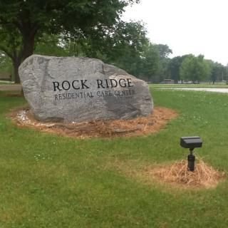 An engraved rock sign for Rock Ridge Residential Community set in a grassy area with trees.
