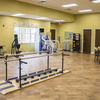 A spacious physical therapy room equipped with various exercise machines and rehabilitation tools.