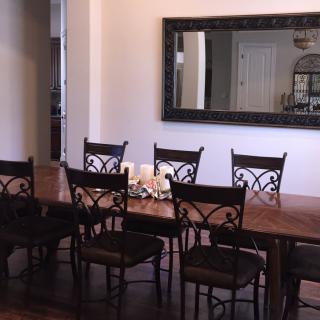 A dining room featuring a wooden table with eight chairs and a large wall mirror.