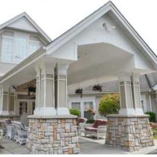 A large residential entrance with a covered porch and stone pillars.