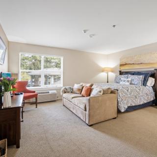 A spacious and well-lit bedroom featuring a large bed, sofa, and elegant decor.