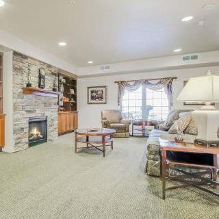 A cozy living room with a fireplace, comfortable furniture, and large windows letting in natural light.