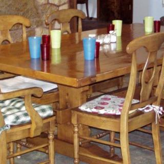 A wooden dining table with cushioned chairs and colorful candles arranged on top.