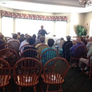 A group of people seated in a room, listening to a presentation.