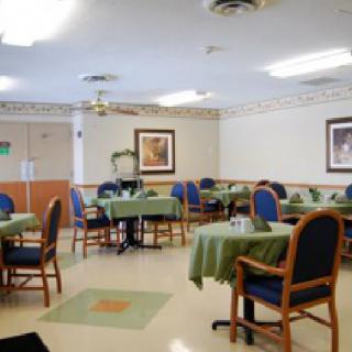A dining area with tables and chairs, decorated with green tablecloths.