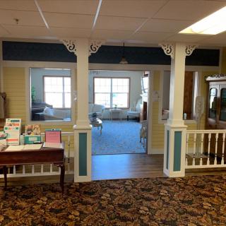 A cozy interior space featuring columns, carpeted floor, and large windows.