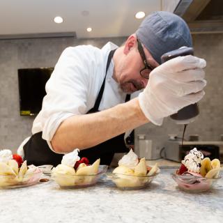 A chef carefully prepares a series of elegant desserts.