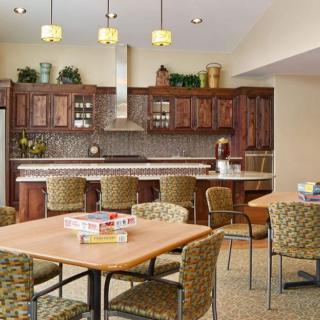 A spacious kitchen and dining area featuring wood cabinetry, multiple seating options, and decorative lighting.