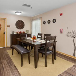 A modern dining room with a wooden table, chairs, and bench, featuring wall art and stylish decor.