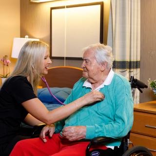 A nurse performs a health check-up on an elderly patient in a care facility.