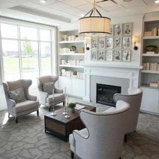 A cozy and modern living room with a fireplace, elegant chairs, and built-in bookshelves.