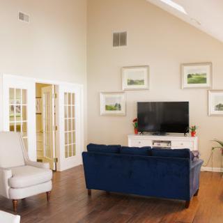 A cozy living room featuring a stylish blue sofa, a white armchair, and elegant wall art.