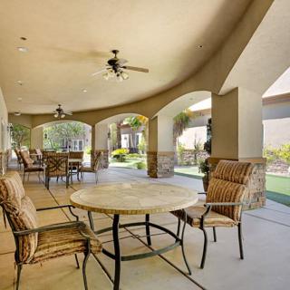 A spacious covered patio with a dining area overlooking a garden.